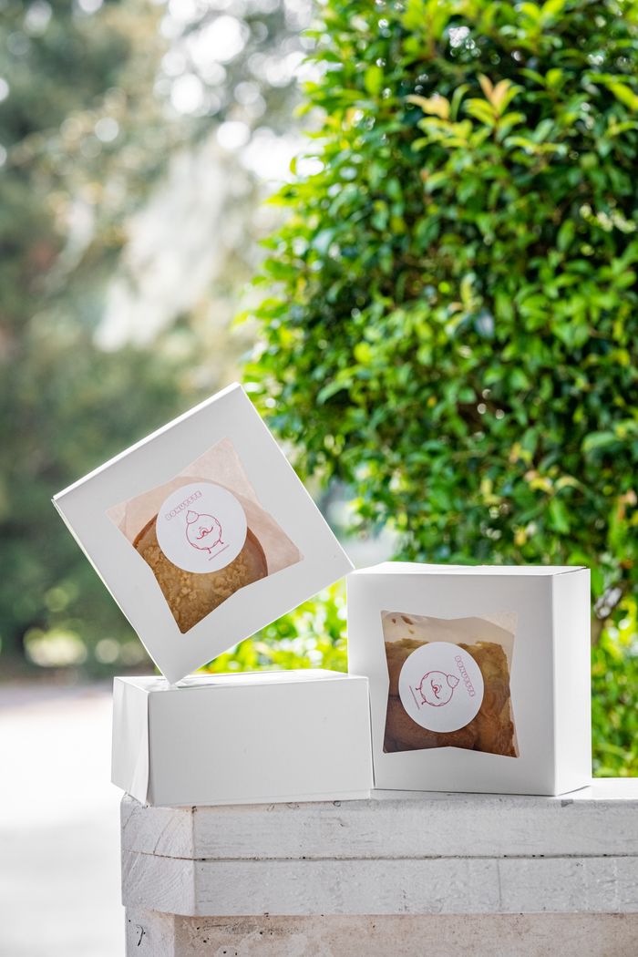 why-choose-us Three white boxes with donuts, displayed outdoors on a stone ledge.